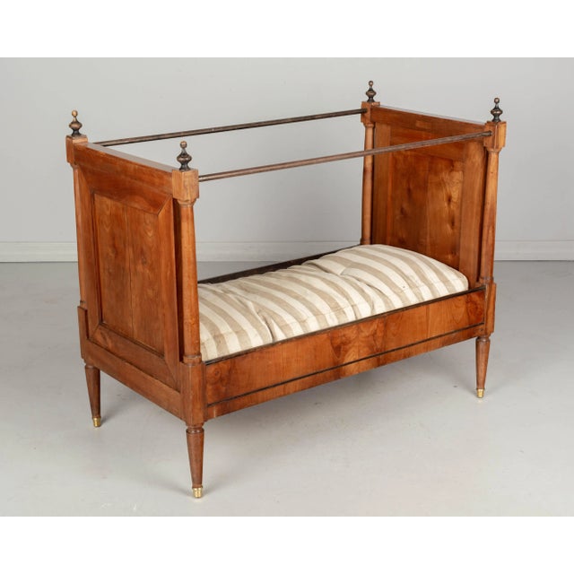 A 19th century French Napoleon III Period child's bed made of solid cherry wood, with column form supports and iron...