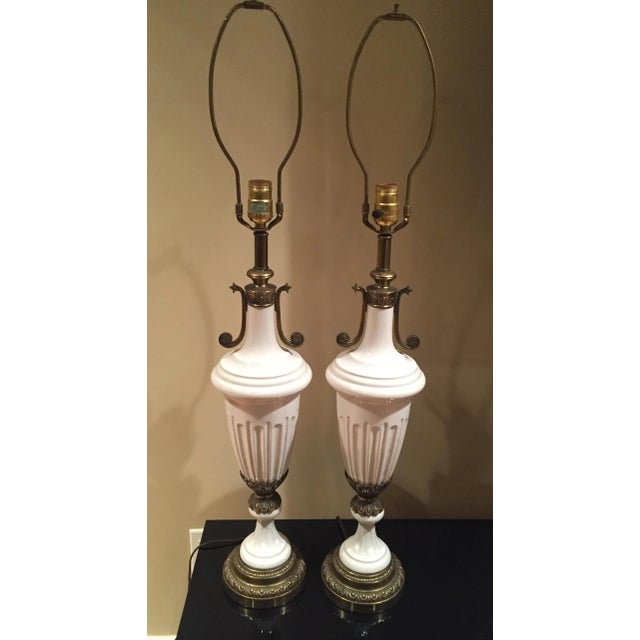 Sophisticated pair of white ceramic fluted lamps. Sculptural fluted body accented with cinched brass detail. Unmarked....