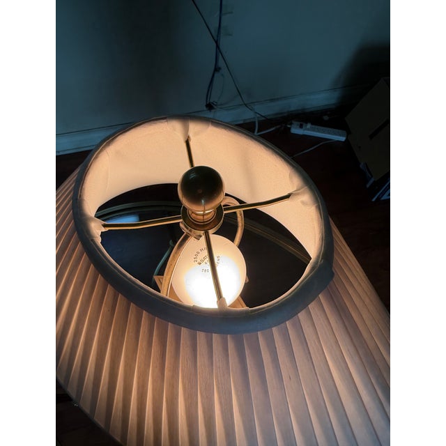 A table lamp by Haig featuring a solid brass diamond-shaped column with a stepped brass base and decorative feet. Finished...