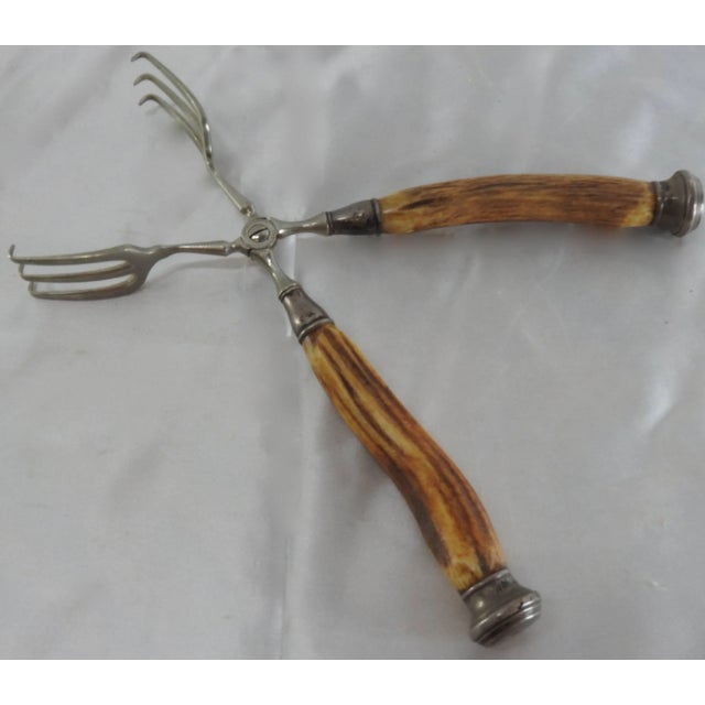 A nice pair of vintage sterling silver tongs with horn handles. The German tongs feature carved Horn handles with sterling...