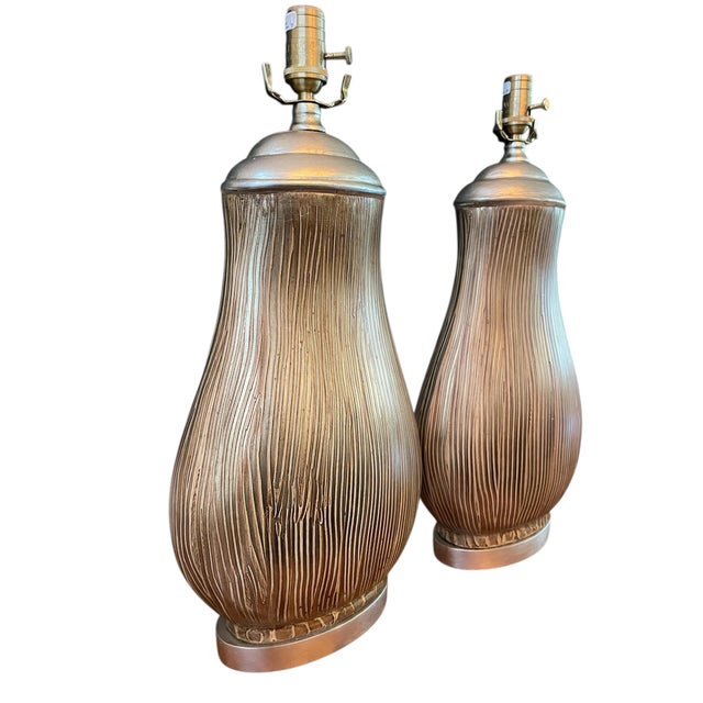 A sculptural pair of ceramic table lamps by Wildwood, featuring elegant vertical striations and a softly reflective...