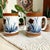 Elevate your coffee experience with the Holt Howard Stoneware Coffee Mug Set, featuring an exquisite abstract blue flowers...