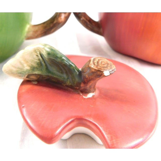 This is a set of Sakura Apple Orchard sugar bowl (red apple) and creamer (green apple). The sugar bowl has a leaf shaped...