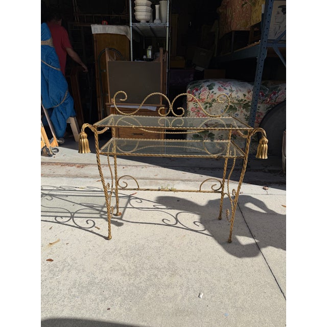 Striking vintage Hollywood Regency gilt metal vanity table featuring an ornate twisted-rope frame, scrolling flourishes,...