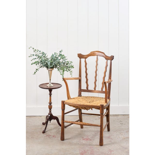 This Arts & Crafts armchair showcases carved, scalloped back slats and a solid elm frame with handwoven rush seats. The...