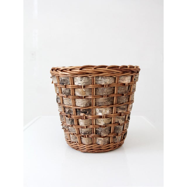 A vintage handmade basket combining woven wicker with natural birch bark bands, giving the piece a richly textured surface...