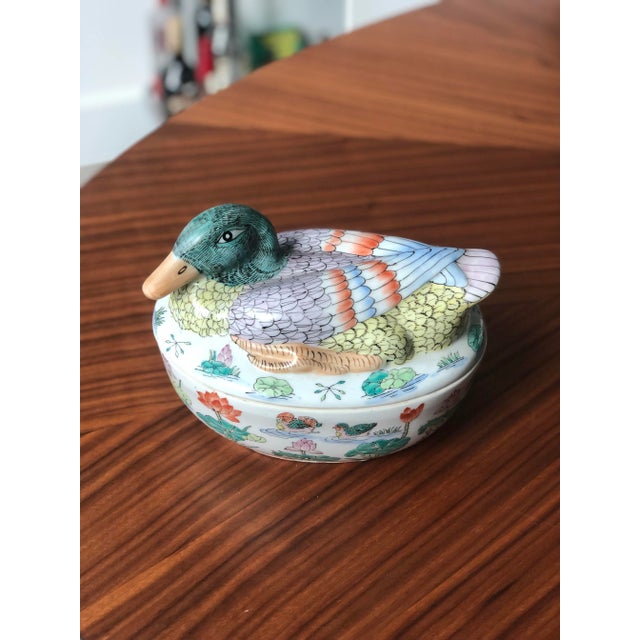 This expertly hand-painted Chinese export piece is a beautifully detailed mallard sitting atop an oval nest that is...