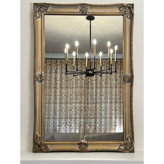Soft gold paint with a light gray wash encompasses this French Provincial style wall mirror. The mirror is surrounded by a...