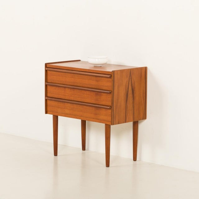 Small Danish vintage teak chest of drawers from the 1960s. The dresser represents a classic Scandinavian mid-century...