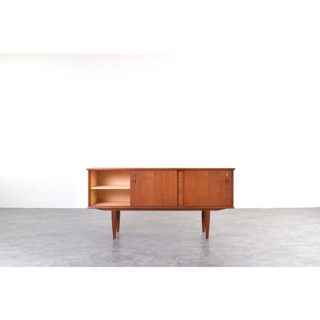 This teak sideboard was manufactured in Denmark in the 1960s. The piece of furniture has four drawers and a sliding,...