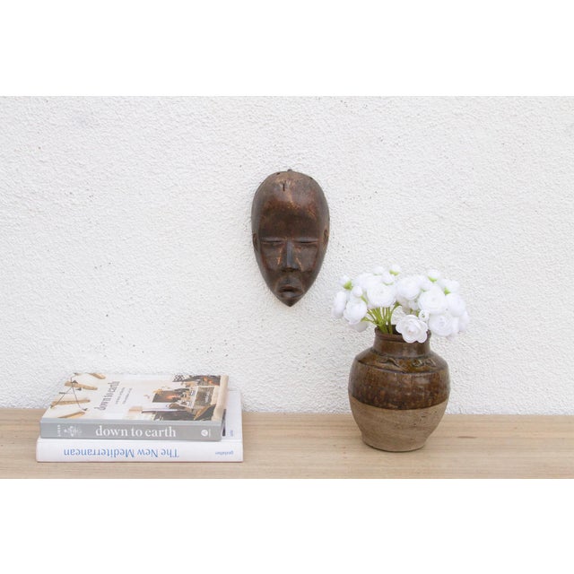 This captivating African mask embodies a sense of quiet contemplation and ancestral presence. The simplified facial...
