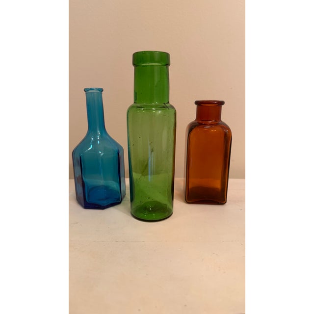Three small vintage jars in three different shapes and three colors--deep aqua, bottle green and amber brown--to brighten...