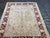 Design Plus Gallery presents a 6ft 4in × 8ft 5in Hand-Knotted Pak-Veg Floral Border Area Rug. The rug has a beige central...