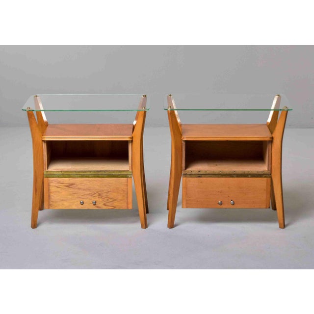 This matched pair of Italian postwar bedside tables is constructed in blonde walnut with four splayed, outward-curving...