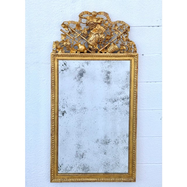 Neoclassical style giltwood and gesso mirror. The rectangular mirror plate within a leaf-tip carved surround, surmounted...