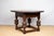 A low, round oak table, Spanish Revival style, c. 1930, American. Featuring a dark stained finish, a square base with cup...