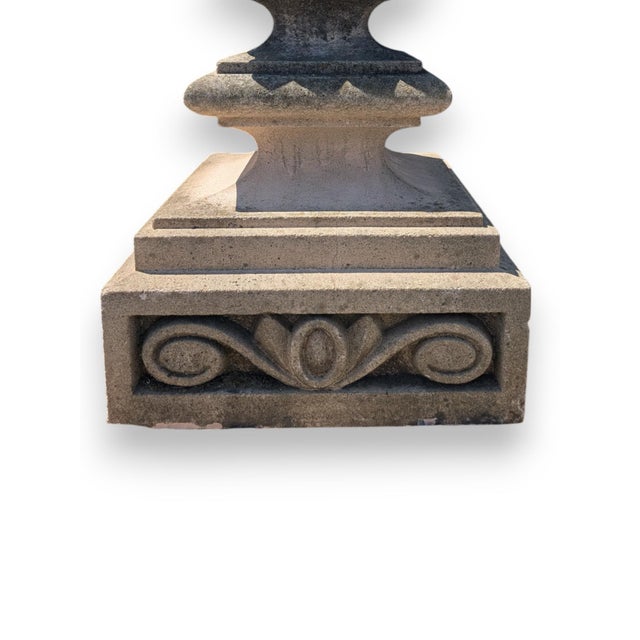 Cast stone garden plinths with large finials. The plinths have a Romanesque design supporting a decorative pineapple...