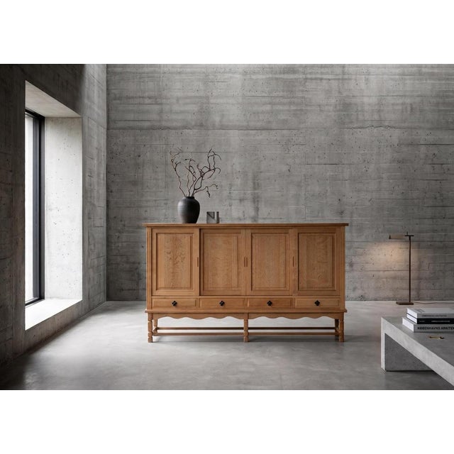 Oak sideboard attributed to Danish designer Henning Kjærnulf, crafted in Denmark during the 1960s. Designed in a...