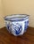 A classic blue and white porcelain planter, rendered in a softly faceted, scalloped form that feels both tailored and...