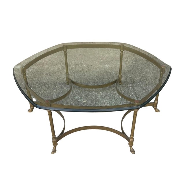 A sophisticated vintage round brass coffee table in the style of LaBarge, featuring a beveled glass top and gracefully...
