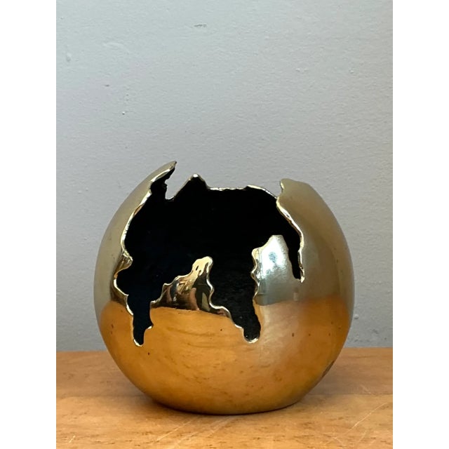 Sculpted with a dynamic, fractured spherical silhouette and bold metallic presence, this vintage mid-century modern cast...