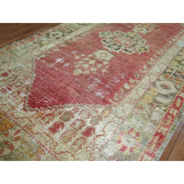 An early 20th century angora wool Oushak rug with a soft watermelon colored ground on an open field and center medallion...