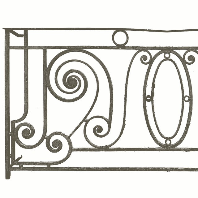 Antique Beaux-Arts style wrought iron balcony railing featuring ornate scrollwork and a central oval medallion....