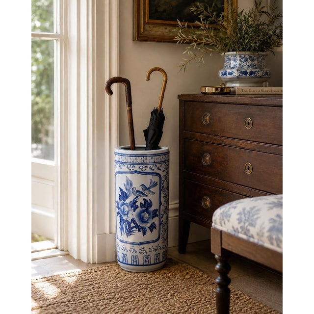 A classic blue and white porcelain umbrella stand in the chinoiserie tradition, featuring finely rendered birds among...