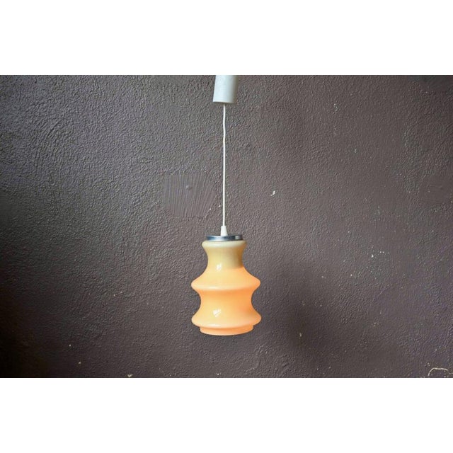 This pretty pendant light is made of a piece of cream-colored glass with pretty wavy effects. The light has a tender and...