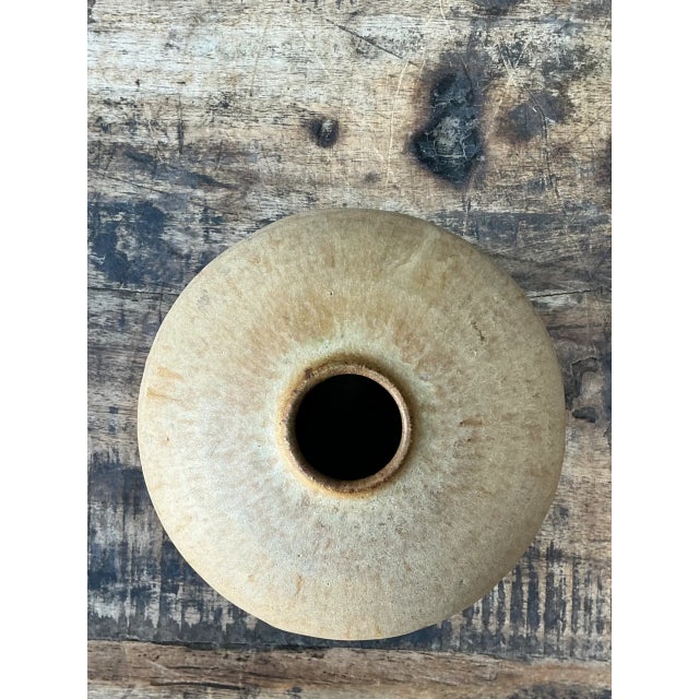 This vintage ceramic vessel embodies the understated warmth of mid-20th-century studio pottery, its rounded form finished...