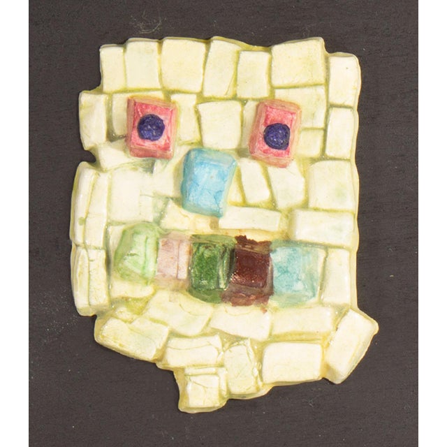 A 1970s ceramic tile by the American artist Mark Bulwinkle (born 1946). This ceramic piece depicts an abstract face...