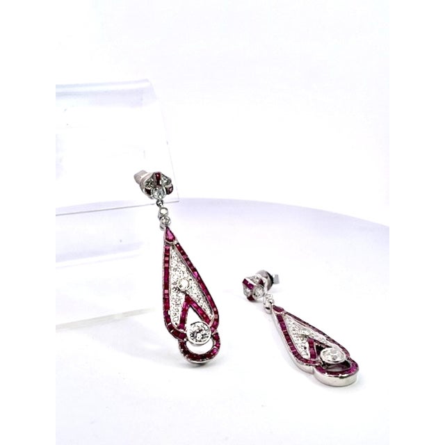 These stunning Art Deco-inspired drop earrings feature an elegant elongated teardrop silhouette set in gleaming white gold...