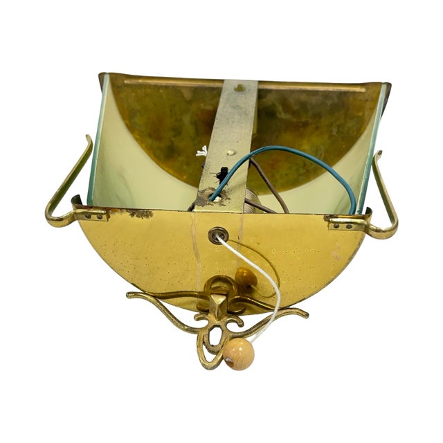 A decorative art glass vessel set in an ornate brass frame, designed in an elegant vintage style. The glass, in a...