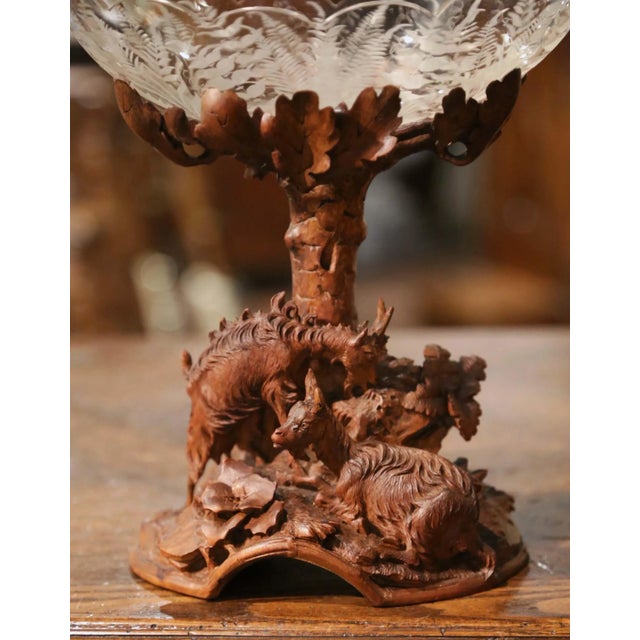 A finely carved walnut base depicting an alpine woodland scene gives this antique Black Forest centerpiece its distinctive...