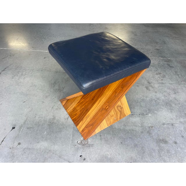 Sculptural corkscrew ottoman by American Leather featuring a striking geometric walnut base with a deep navy leather...