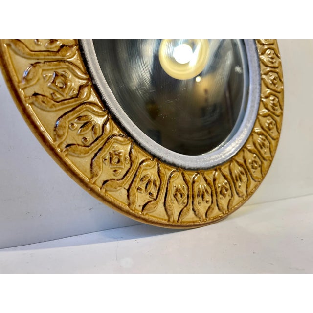 A decorative circular wall mirror in ochre yellow glazed ceramic. It was made in Italy during the 1970s, probably by...
