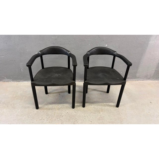 A stylish pair of Postmodern armchairs featuring sculptural black molded plastic construction with integrated armrests....