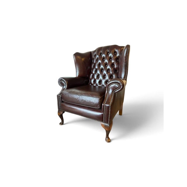 Chesterfield, Wingback Armchair in brown leather with deep-button tufting, they feature rolled arms, brass nailhead trim....