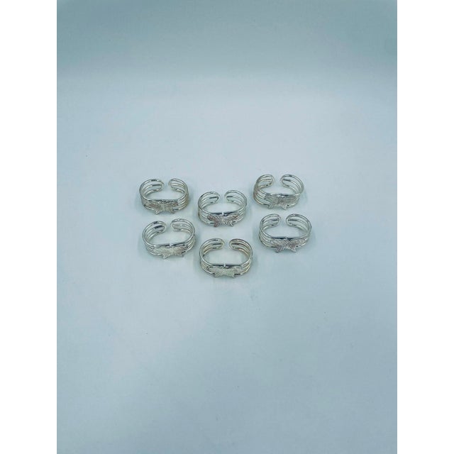A set of vintage-style napkin rings, crafted from silver-colored metal. The napkin holder features a multi-layered design...