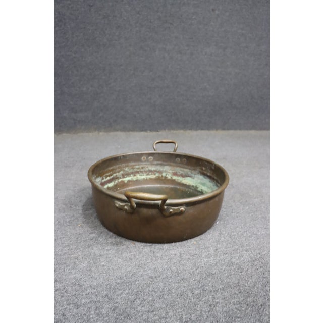 Antique solid copper jam pan featuring a classic low, wide form with rolled rim and riveted brass loop handles....
