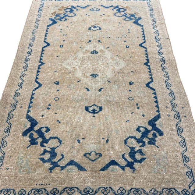 This understated antique rug is defined by its simplicity and graceful proportions. A small ivory geometric medallion sits...
