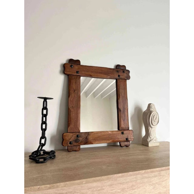 A handmade French wall mirror in solid wood with metal accents. This vintage Brutalist mirror has a chunky wooden frame...