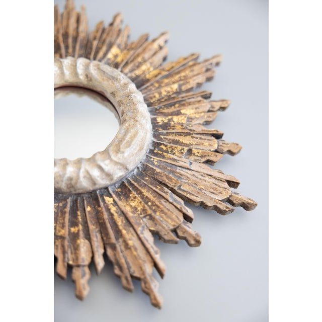 A stunning vintage French gilded wood sunburst mirror. This stylish mirror is surrounded by a silvered decorative trim and...