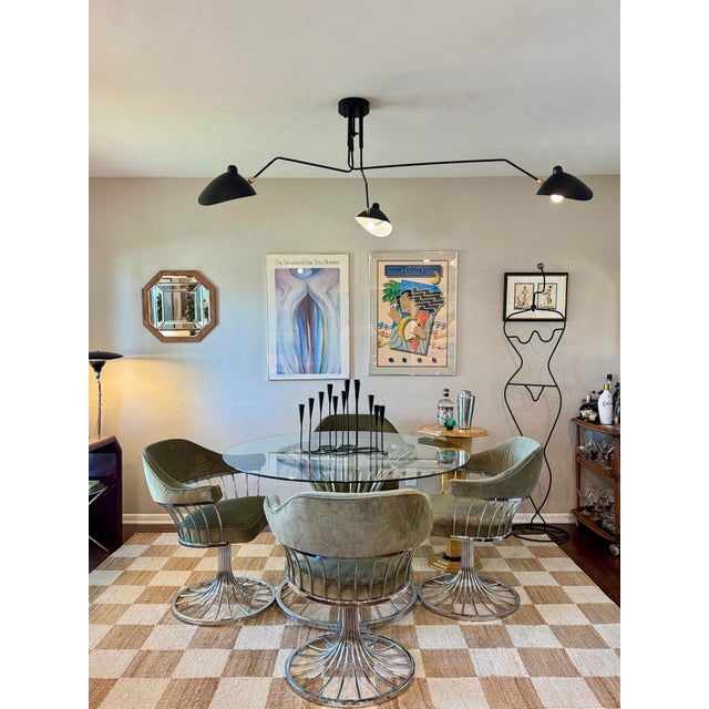 A stylish mid century modern dining set including 4 armchairs and a matching glass top table, all featuring sleek chrome...