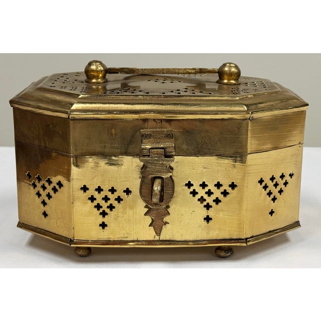 Vintage polished lidded brass cricket box. Perforated pierced design throughout on a footed base. Angular shape. Natural...