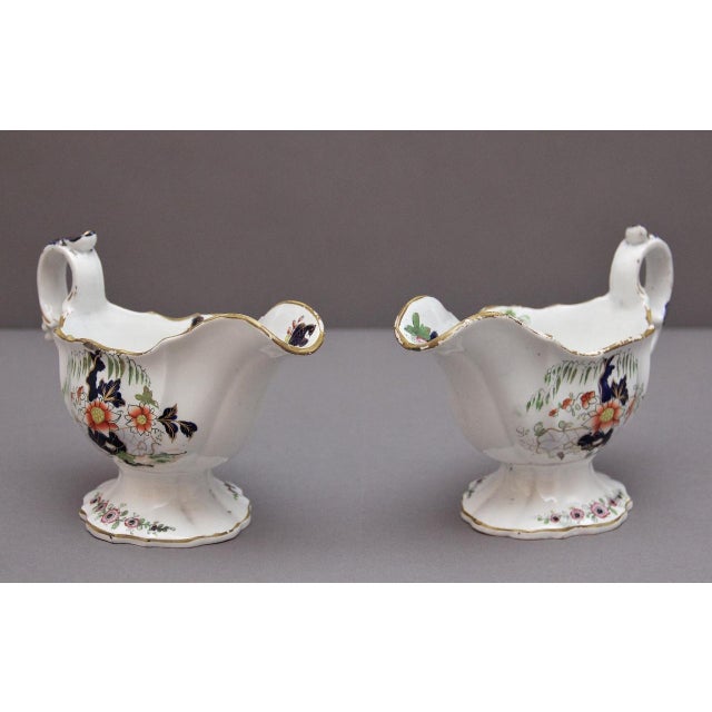 A decorative pair of early 19th Century high footed sauceboats, possibly Worcester porcelain, elegant scroll handles and...