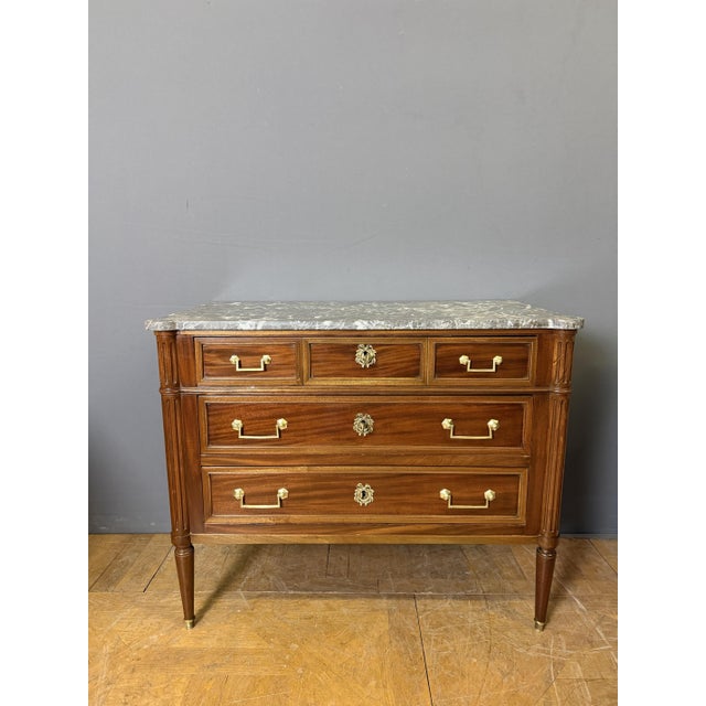 A 19th-century Louis XVI style walnut commode. It features three drawers separated by dividers. The four uprights are...