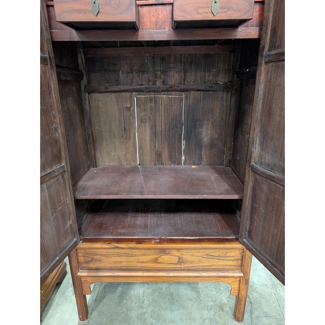 This hardwood cabinet features a warm, rich stained finish and classic paneled double doors with refined molding details....