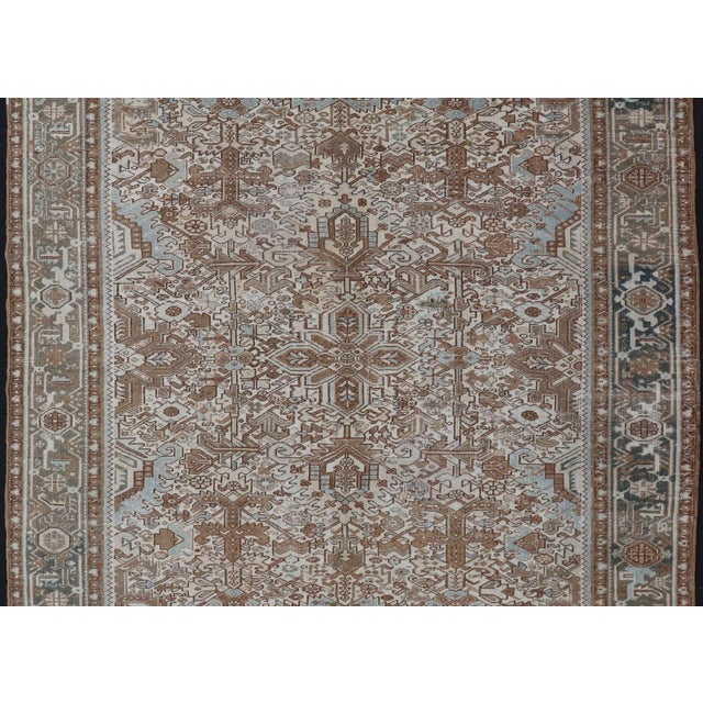 This vintage hand-knotted Persian Heriz rug features an all-over sub-geometric design, enclosed within a complementary,...