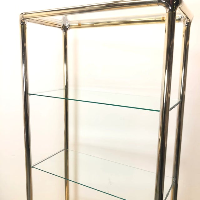 Stunning tubular chrome etagere shelf with shaped corner pieces in brass, styled after Milo Baughman. Very good-excellent...
